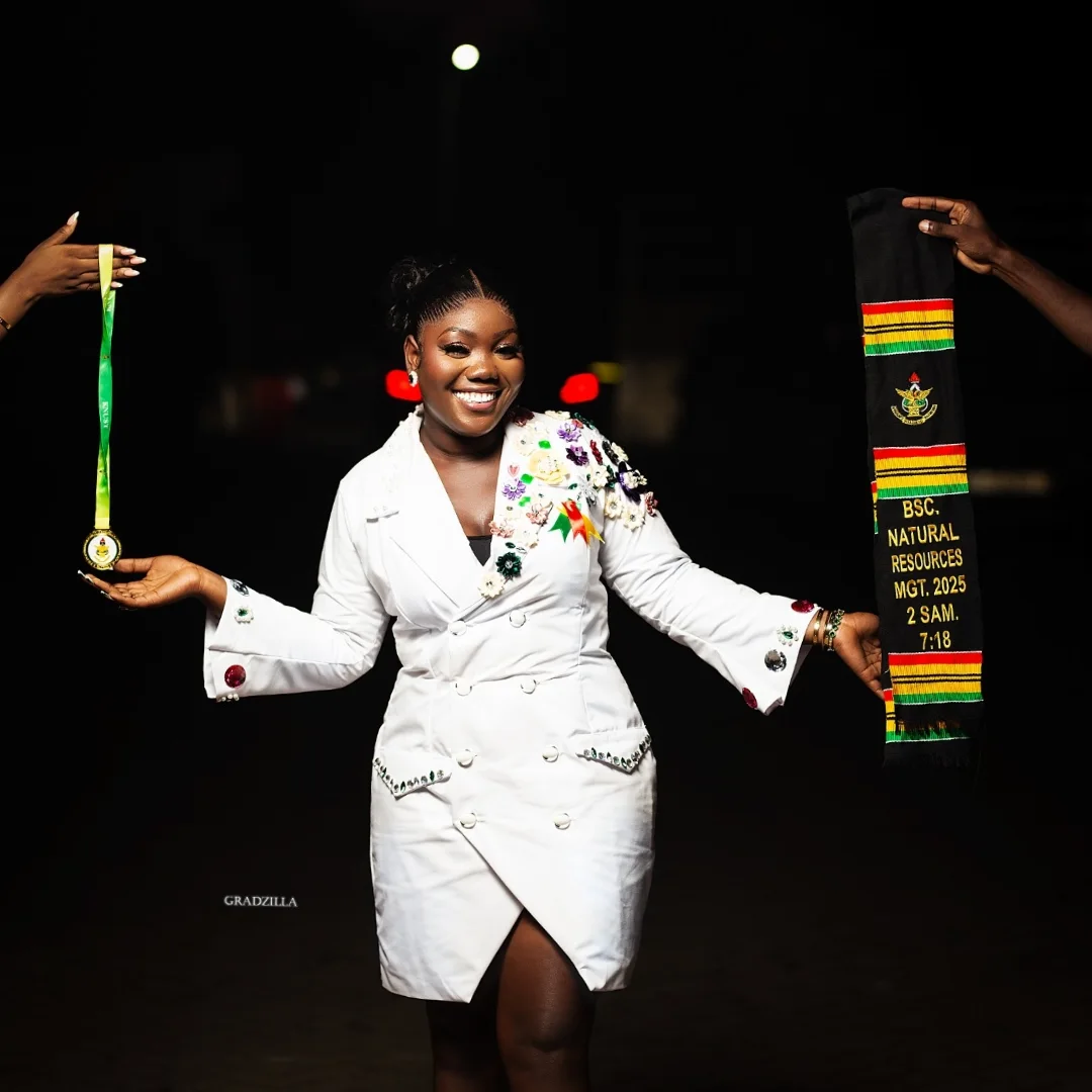 Graduate in an embellished white blazer dress, arms outstretched in celebration at night